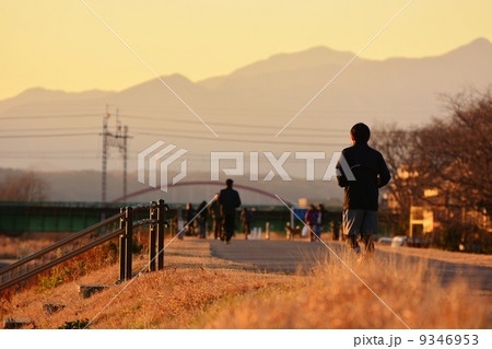 夕方 走る ジョギング 土手の写真素材
