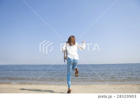 女性 後姿 走る 海の写真素材