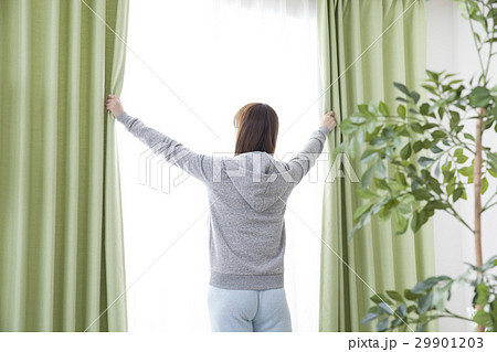 女性 朝 開ける カーテンの写真素材