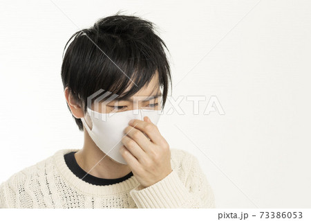 マスク姿の男性/頭痛で頭を抱える/具合が悪い独身男性/	