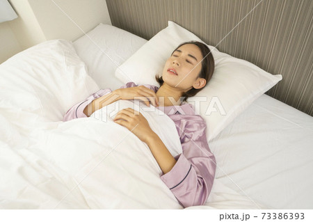 病気で寝込んでいる女性/体調の悪い女性/ベットに寝ている美しい女性