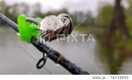 Silver fishing bells are worn on a fishing rod while fishing. Bite-call  signal, at the tip of the rod. A bite alarm will alert you to a bite. Fishing  tackle close-up. 11365671
