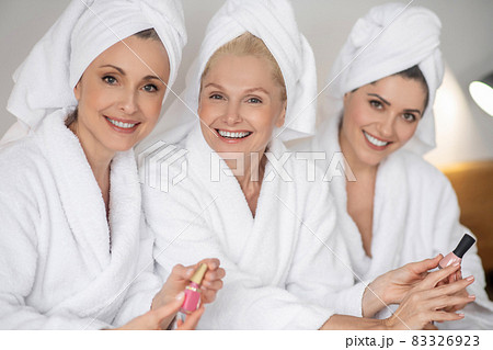 Three diverse young women in underwear holding hands and laughing